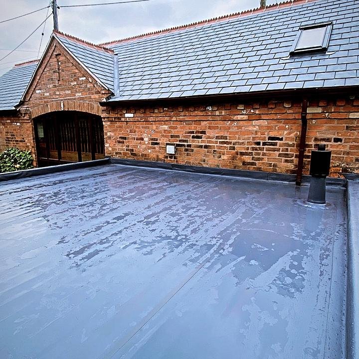 Flat roof beside a slate barn roof