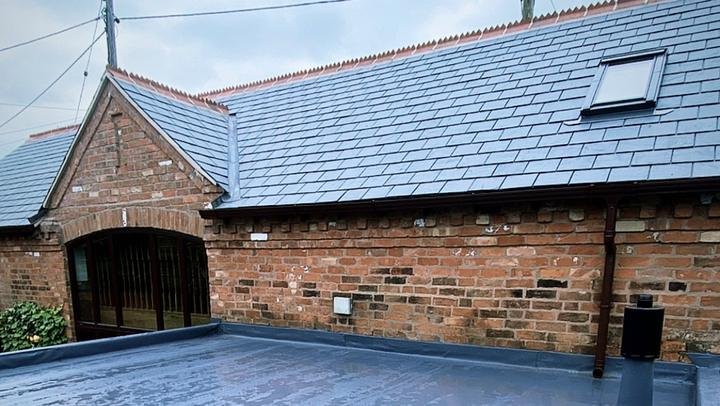 Slate roof and flat roof on a brick barn